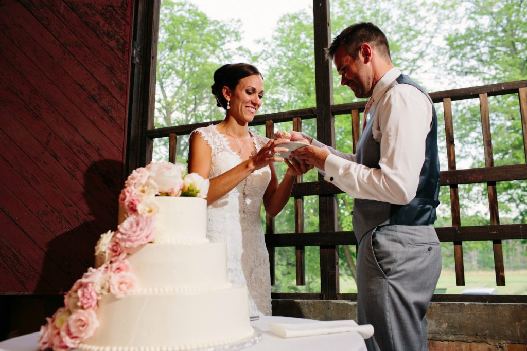 Wedding cake under the large shuttered barn window. 