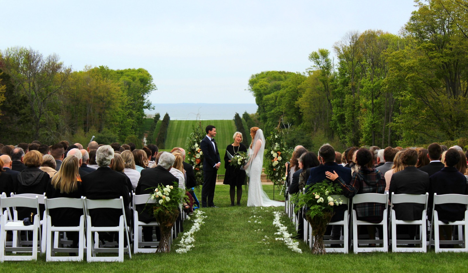Wedding ceremony taking place along the grand allee at The Crane Estate. 